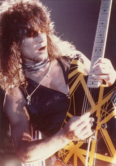 Our History: Eddie Van Halen mid-riff with his yellow striped guitar—fully in the zone and in love.