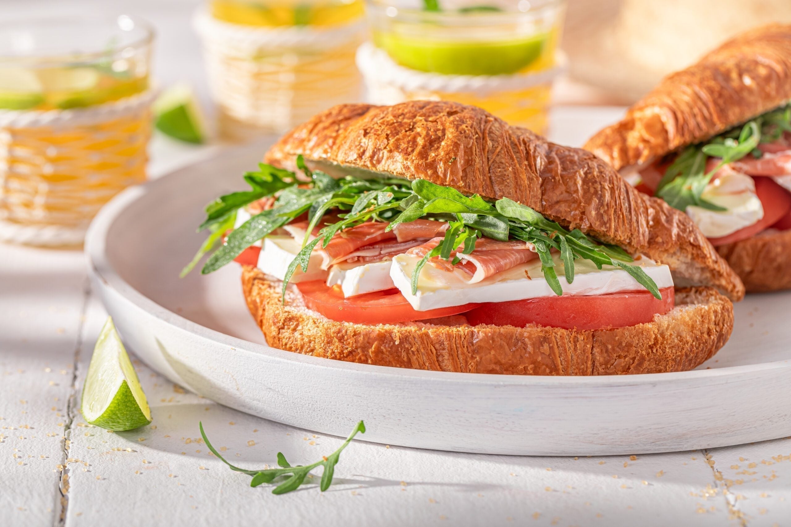 Buttery croissant filled with MouCo Camembert, prosciutto, arugula, and tomato—layers of creamy, savory, and fresh ingredients in one elegant bite.