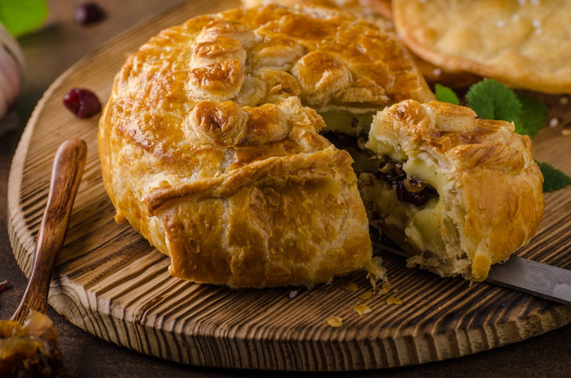 Wheel of MouCo Camembert baked with a savory mushroom topping, served in a pastry crust—melty, earthy, and ready to scoop with crusty bread.