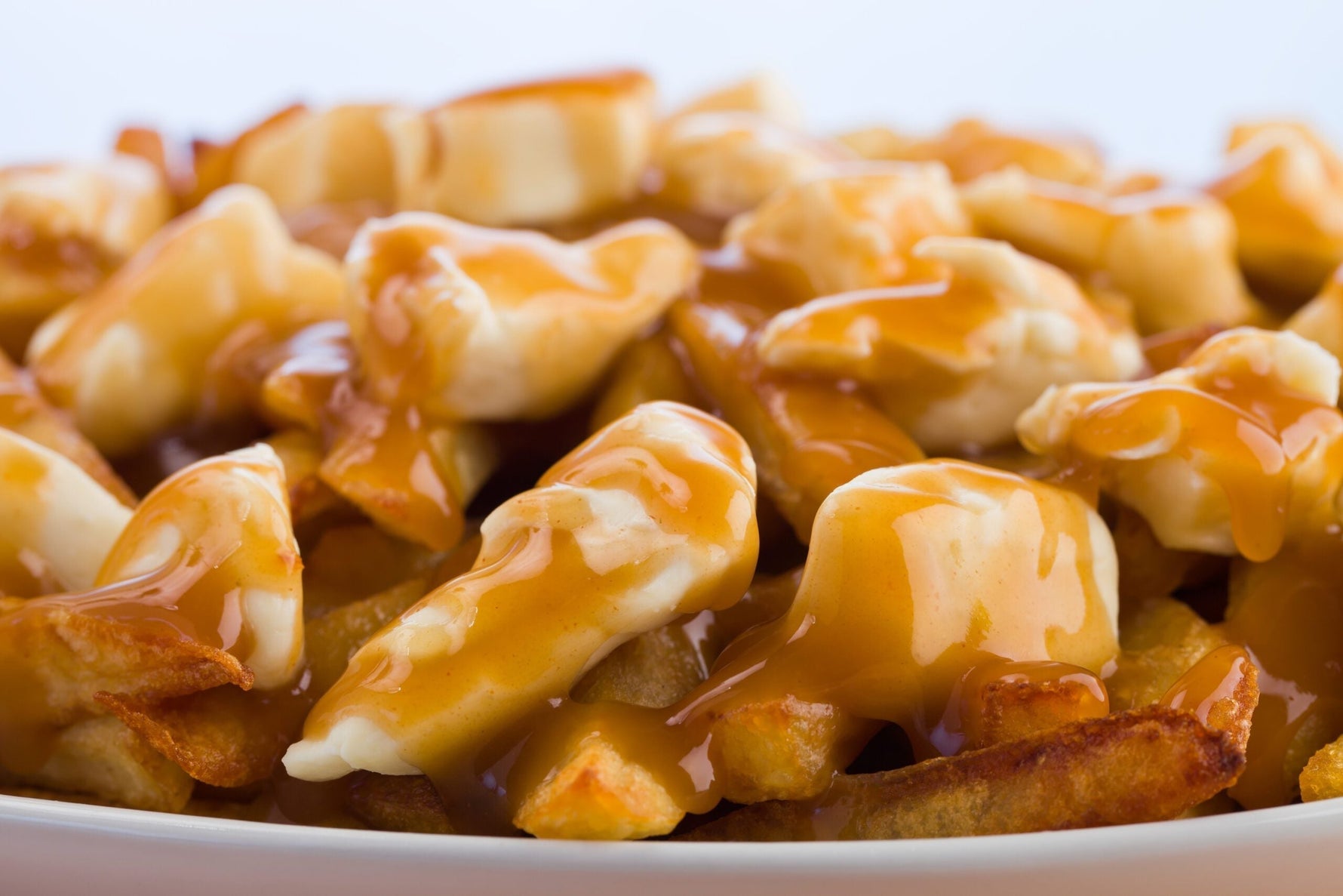 Pile of golden fries smothered in beef gravy and MouCo Cheddar Cheese Curds—melty, squeaky, salty-satisfying poutine that hits every craving hard.