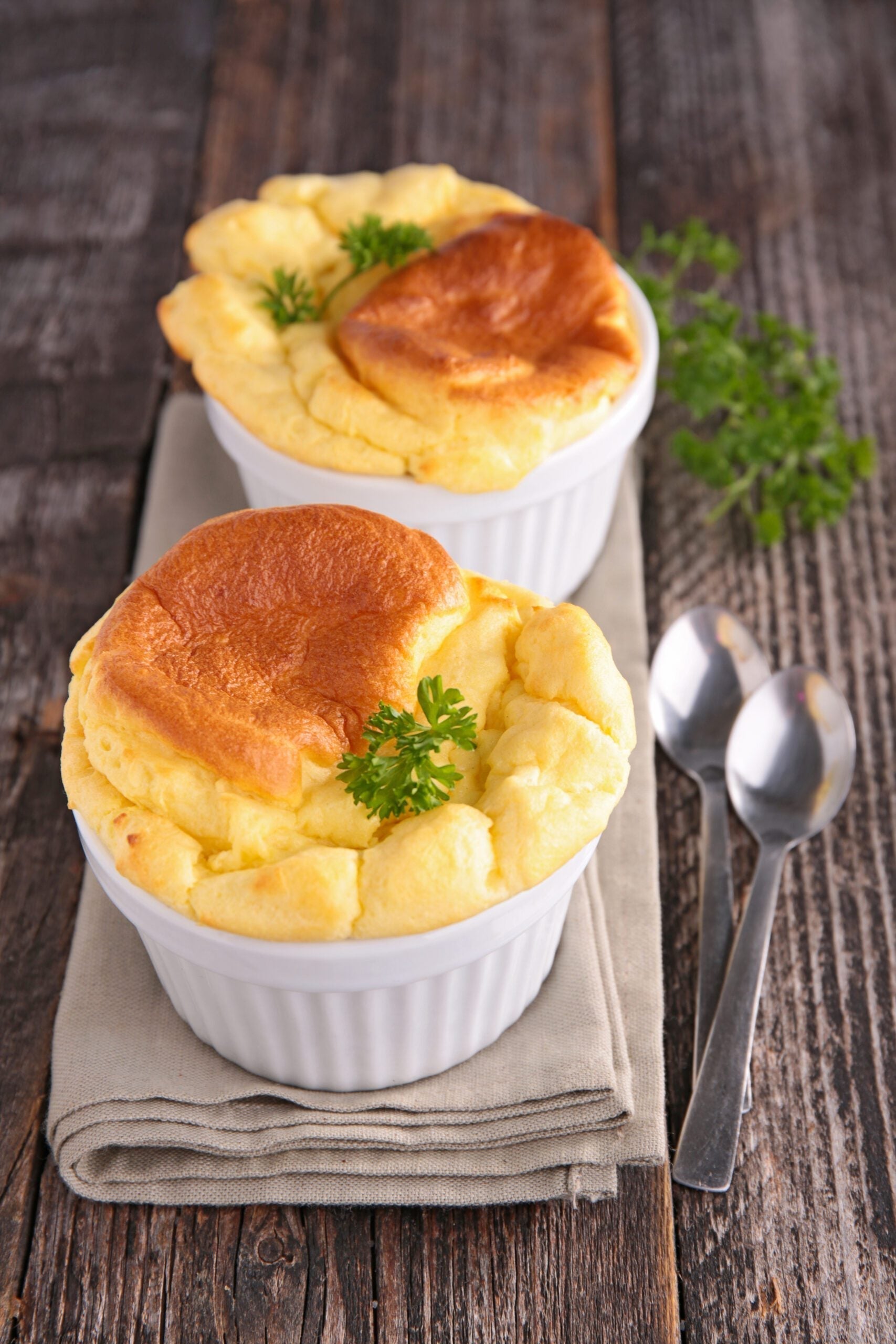 Golden MouCo Camembert cheese soufflé rising tall in a white ramekin—light, airy, and rich with tangy, creamy flavor.