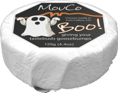 MouCo Boo cheese at an angle with a visible cut, highlighting its creamy texture and playful Halloween-themed rind.