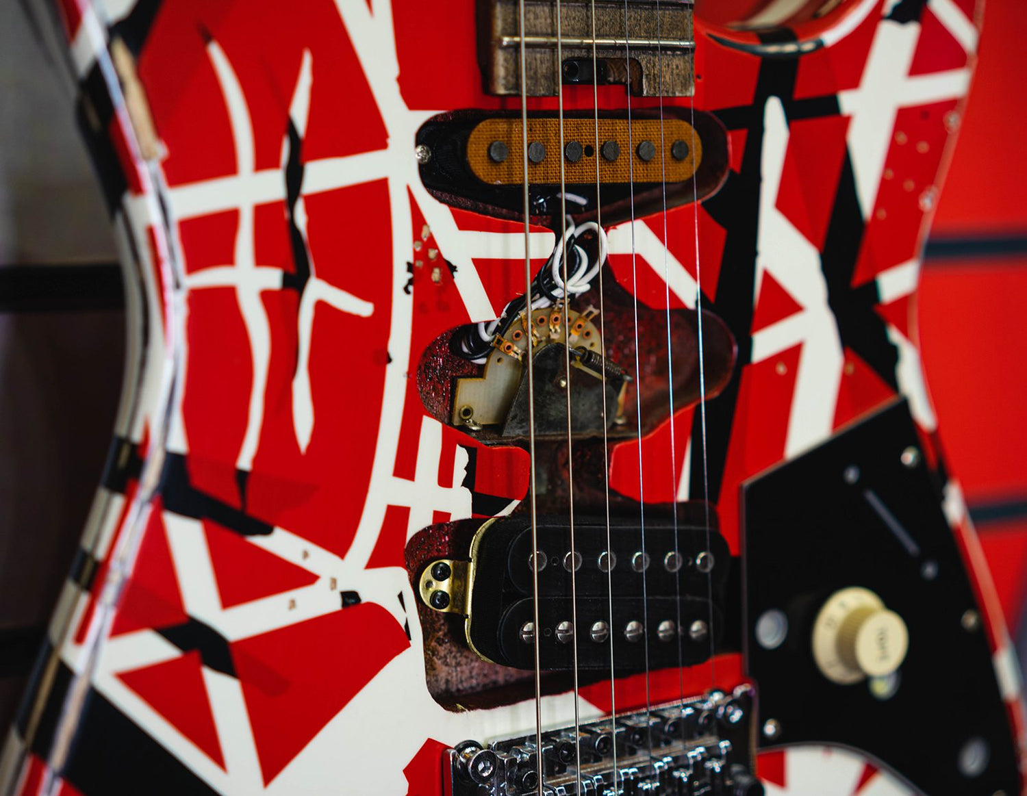 Our History: Close-up of Eddie Van Halen’s Frankenstrat—the legendary red, black, and white guitar that redefined rock tone and style.