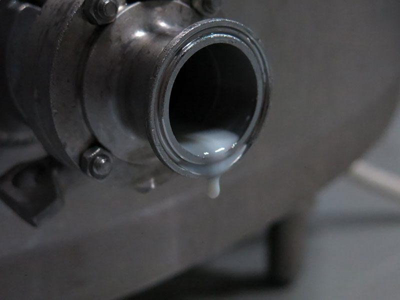 Close-up of MouCo milk tank valve with the last drips of milk before cleaning.